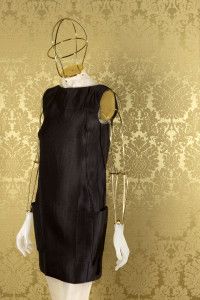 Black satin dress on a mannequin against gold damask, Miu Miu look book 2008