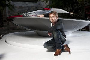 Designer Ora-Ïto crouching by a futuristic concept car, Milan 2011