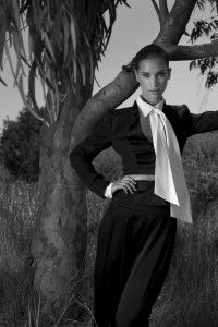 Model in black suit and white bow blouse by a tree, black and white, Greece 2012