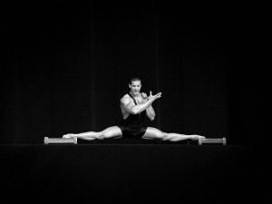 Athlete doing the splits on a dark stage