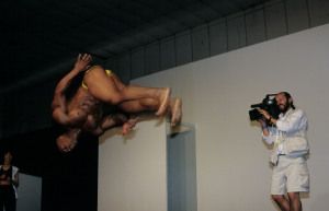 Acrobat leaping over a wall while a cameraman films