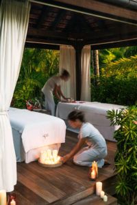 Massage therapists preparing a candle-lit treatment in the tropical spa pavilion, Cheval Blanc St-Barth