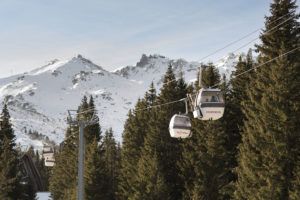 Gondola lift above snowy fir trees, Courchevel, French Alps