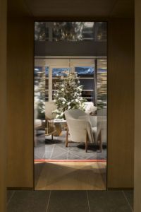 Lounge with Christmas tree seen through a wooden doorway, Cheval Blanc Courchevel