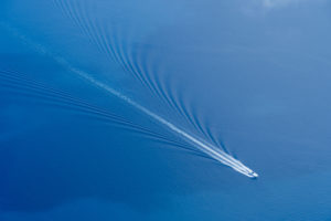 Speedboat wake across deep blue ocean, Maldives, aerial view